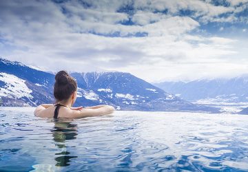Frau im Außenswimmingpool blickt auf die Berge mit Schnee