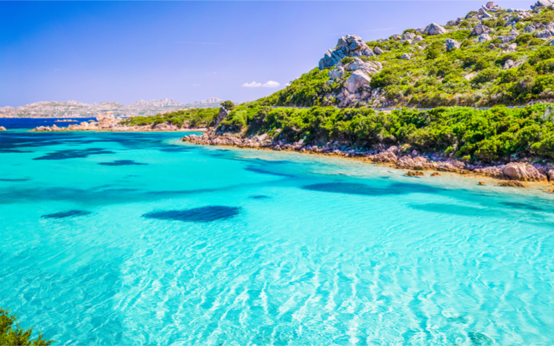 Türkises Meer von Sardinien mit bewaldeten Hügeln im Hintergrund