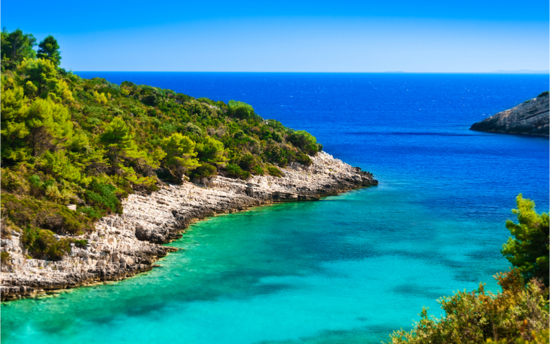 Paradisische Bucht mit kristallklarem, türkisem Meer und Pinien-Bäumen